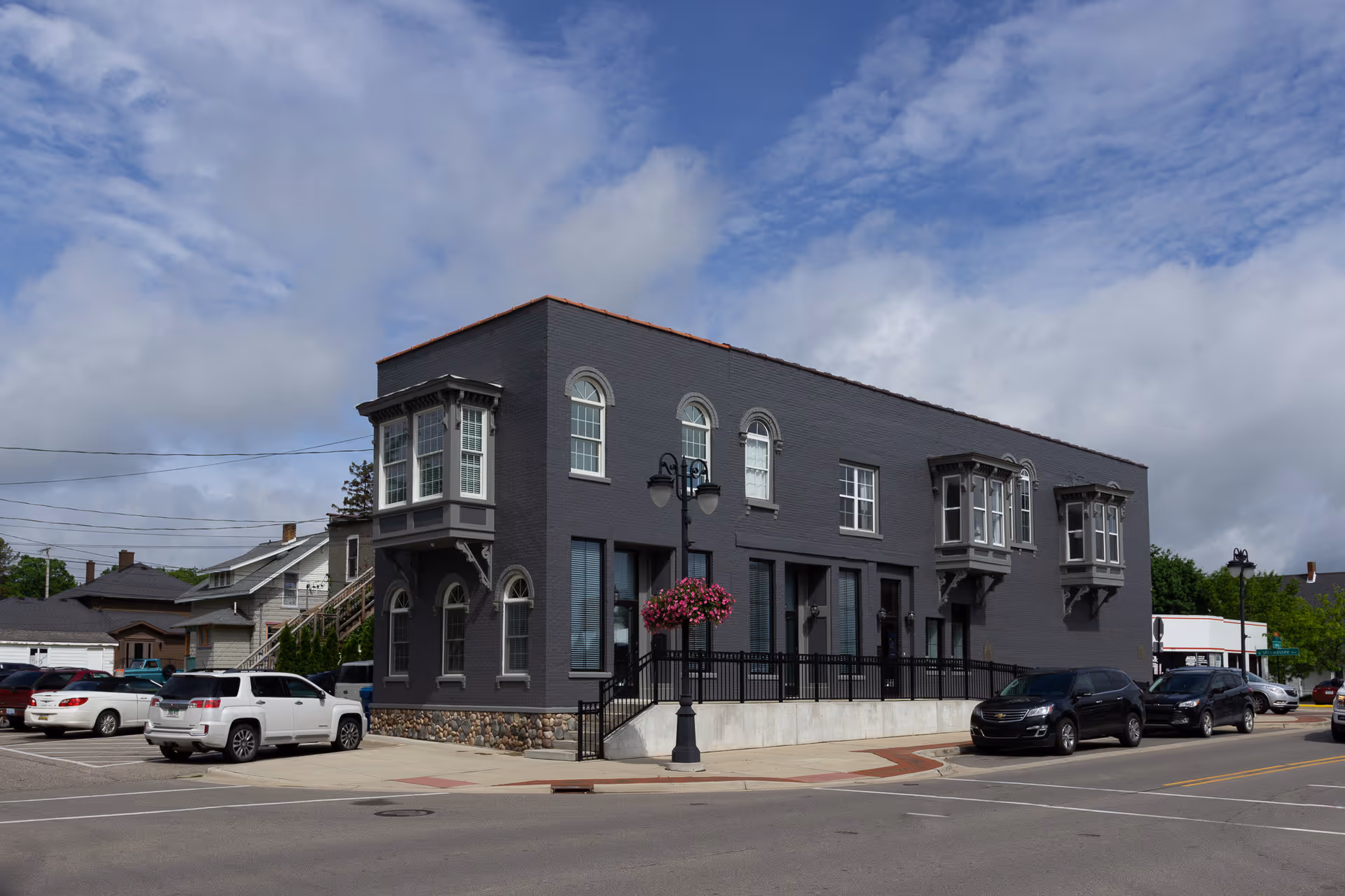 Exterior view of a dark gray rehab facility with parked cars along the street