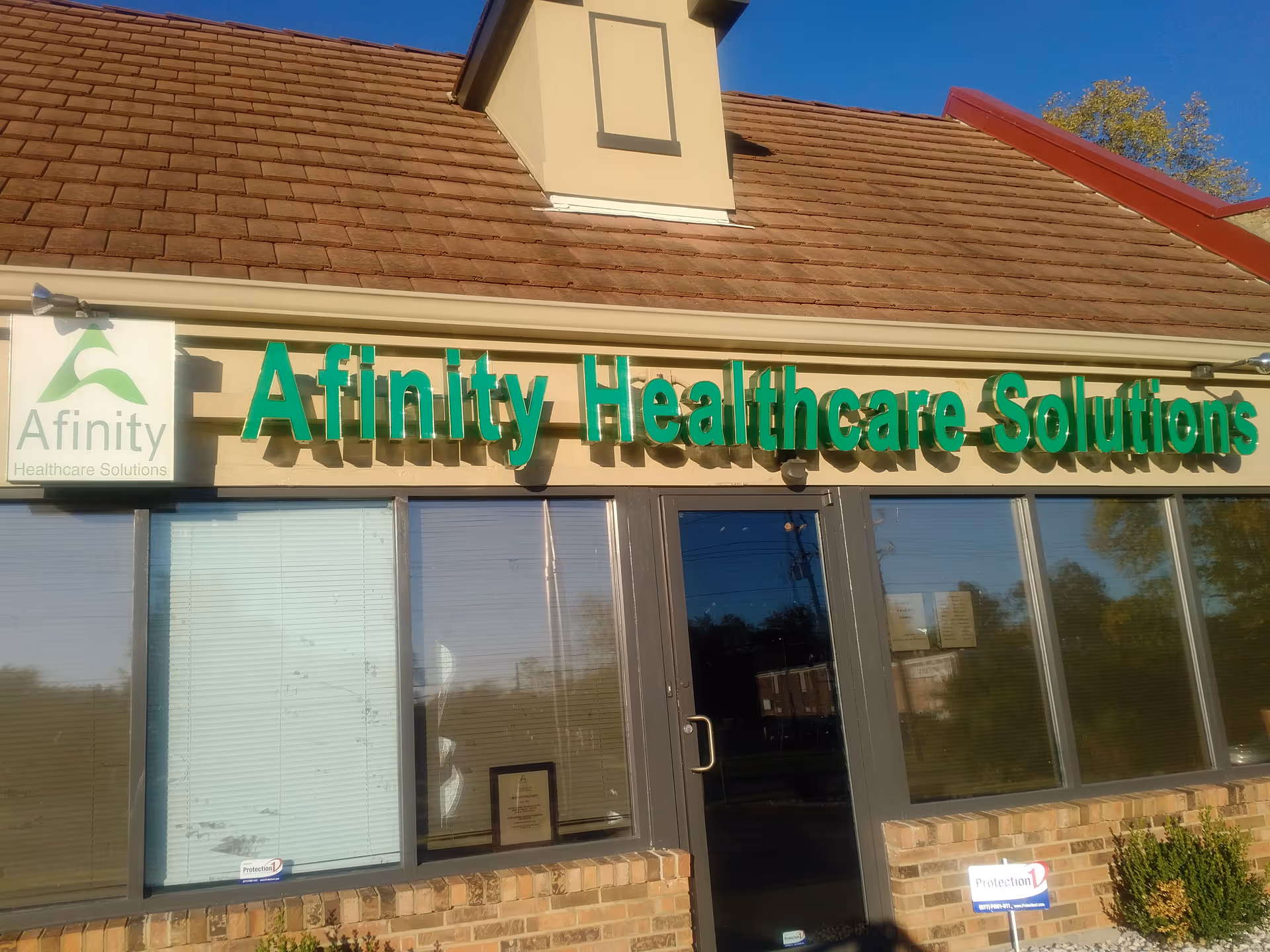 Exterior view of a storefront with green Affinity Healthcare Solutions signage and glass windows.