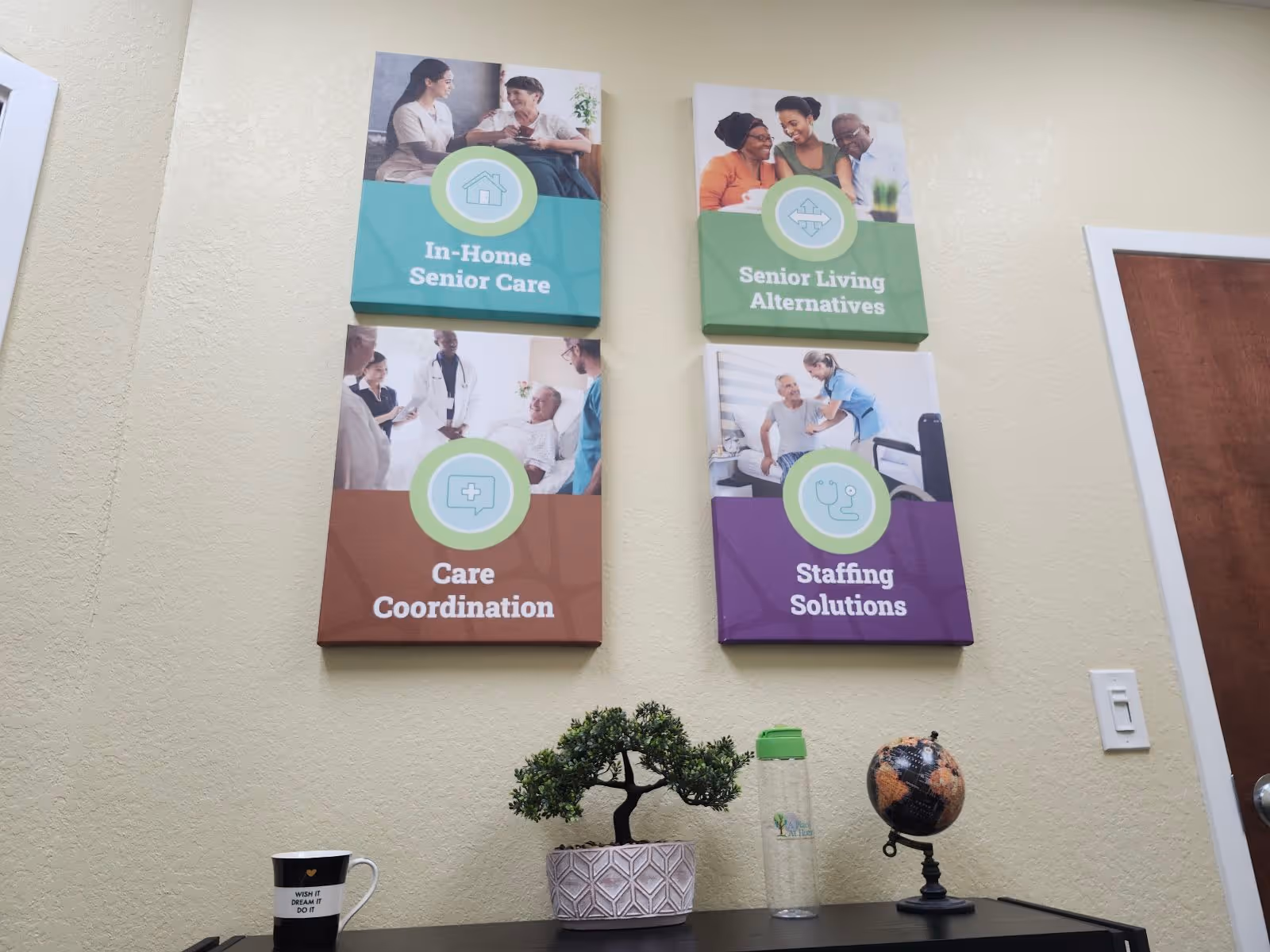 Interior wall with four colorful signs about senior care services and a desk with decor.