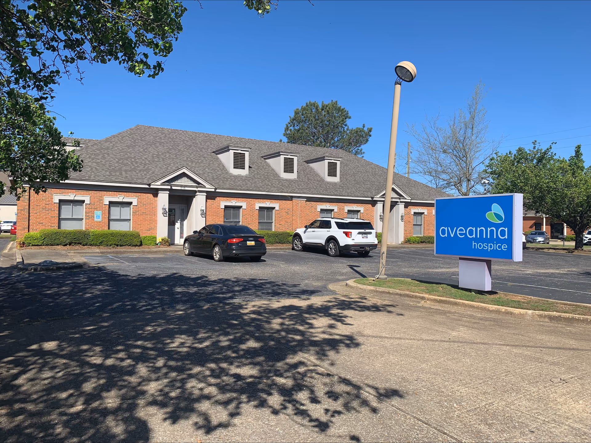 Front exterior of Aveanna Hospice of Montgomery with parking lot and sign.
