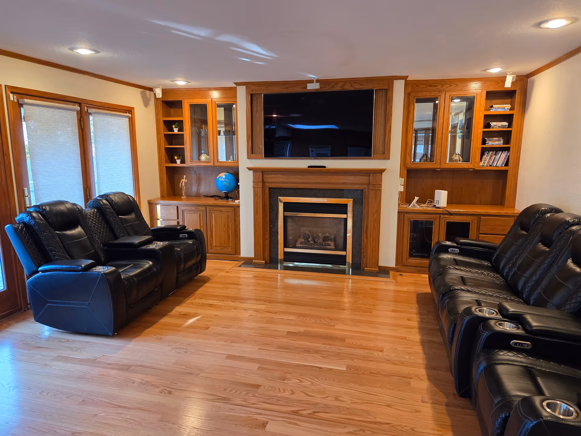 Cozy living room with leather recliners, built-in wood cabinets, and a fireplace.