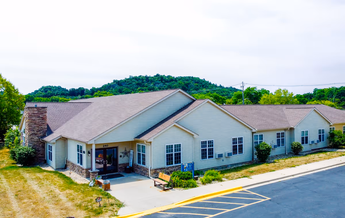 Exterior view of a single-story senior living facility with beige siding and front entrance.