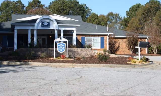 Front exterior of a senior living facility with arched entrance and landscaping.