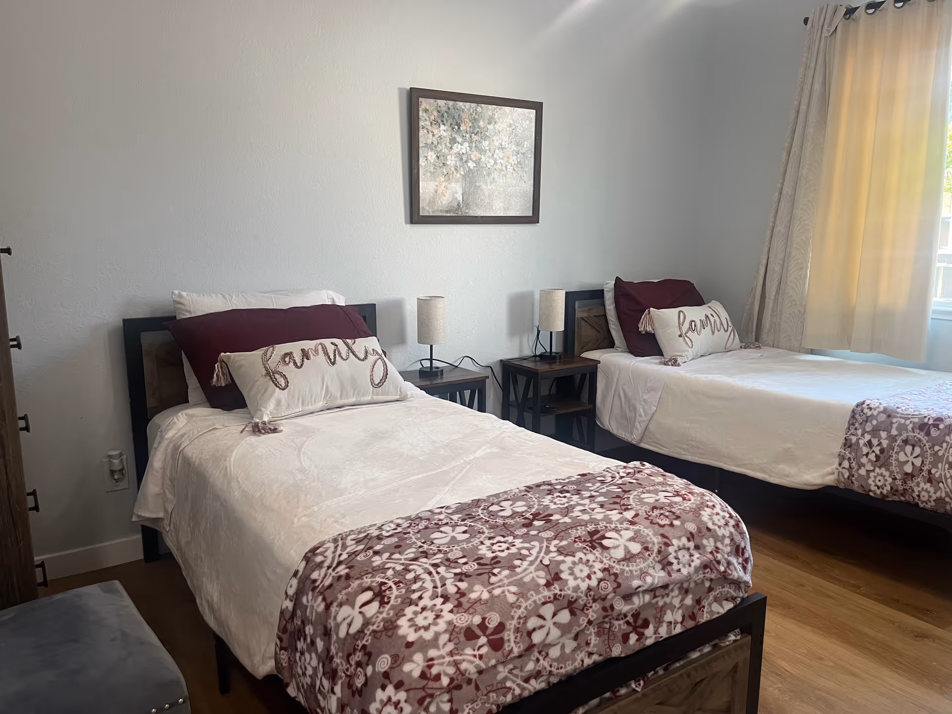 Two twin beds with matching bedding and nightstands in a bright, tidy bedroom.