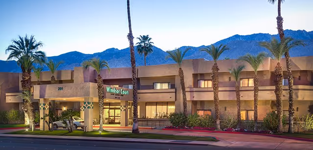 Exterior view of Windsor Court Assisted Living facility with palm trees and mountains