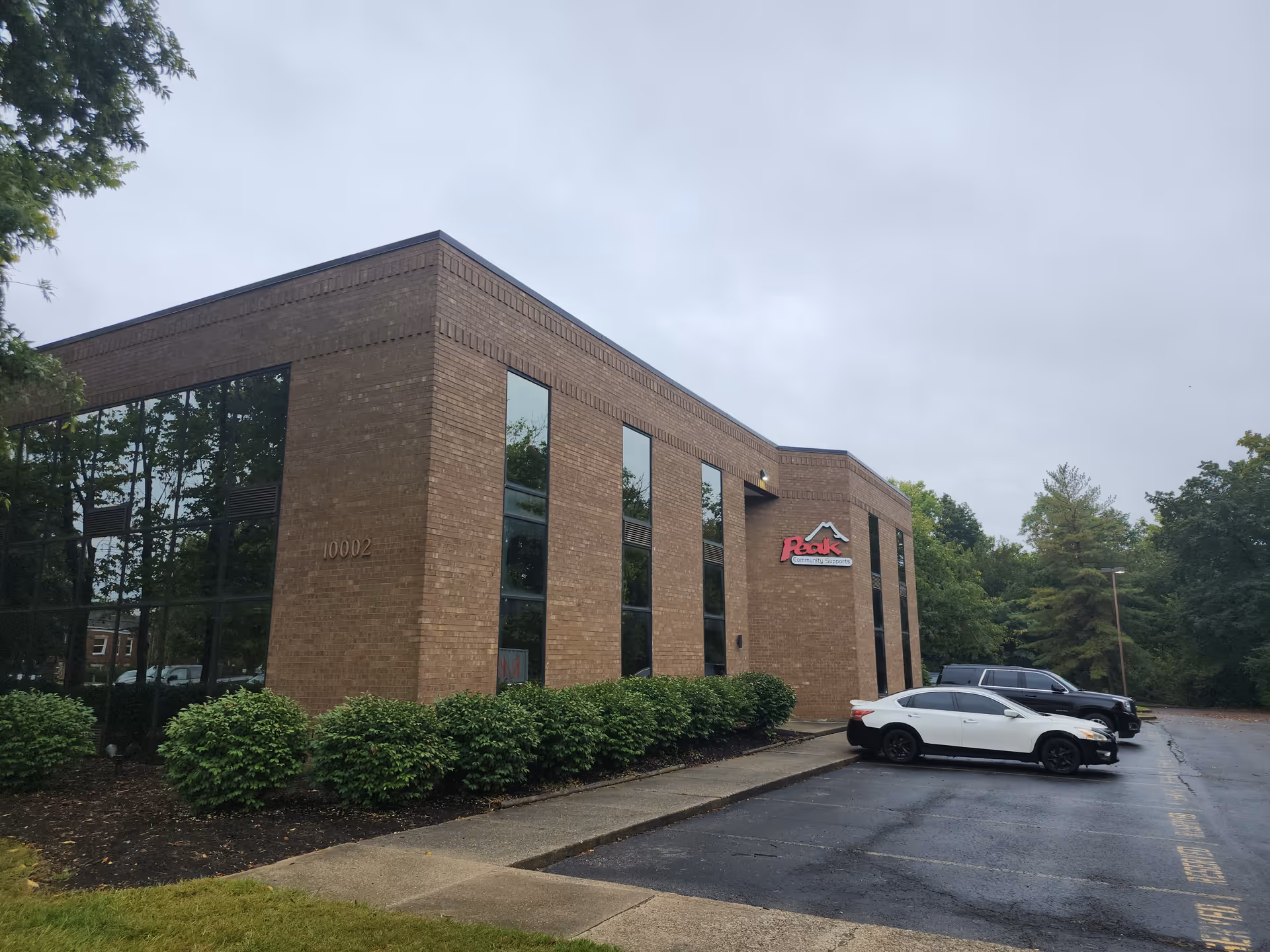 Brick building exterior with large windows and parked cars in front