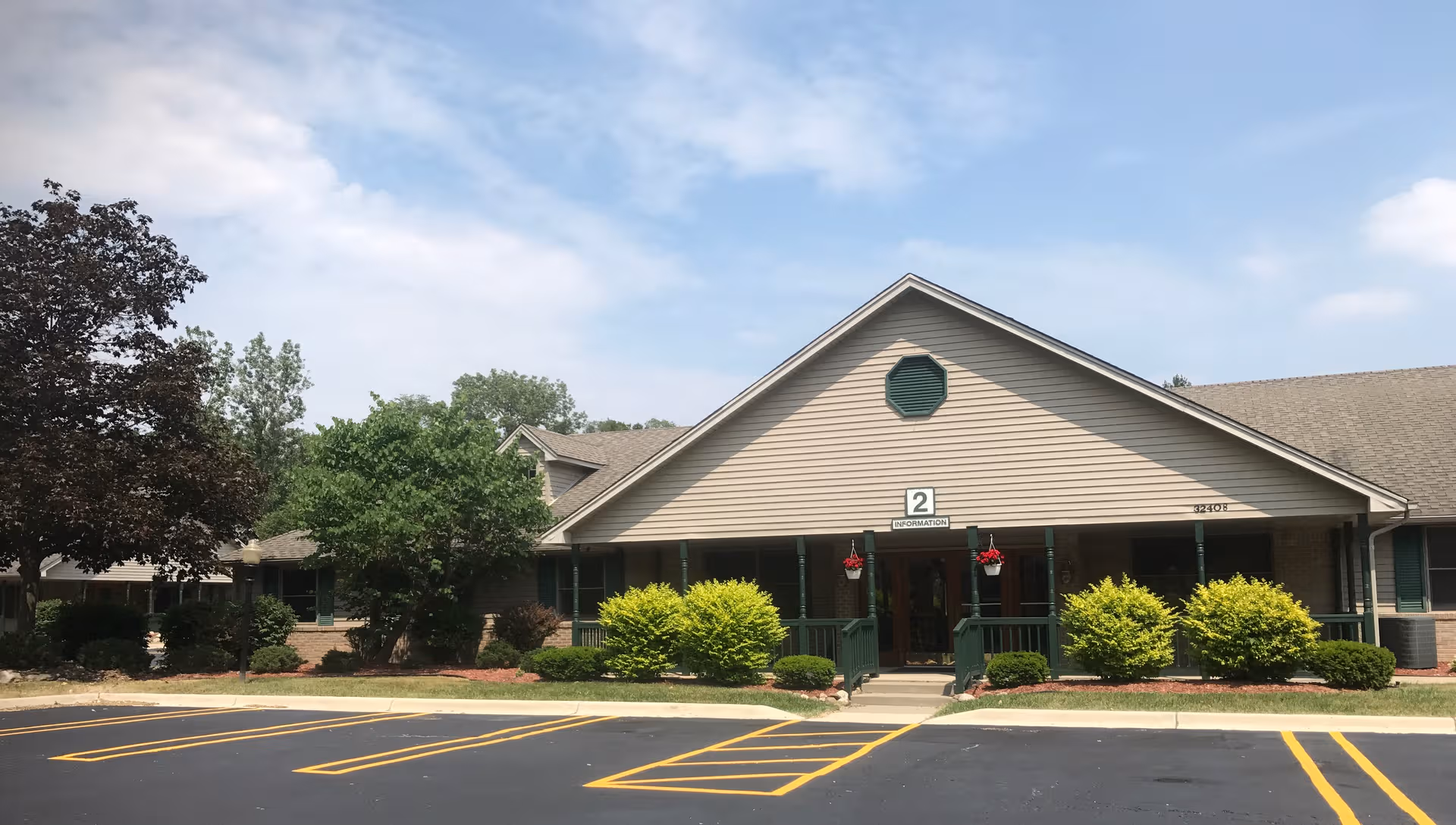 Aspen Assisted Living facility entrance with green shrubs and a paved parking lot.