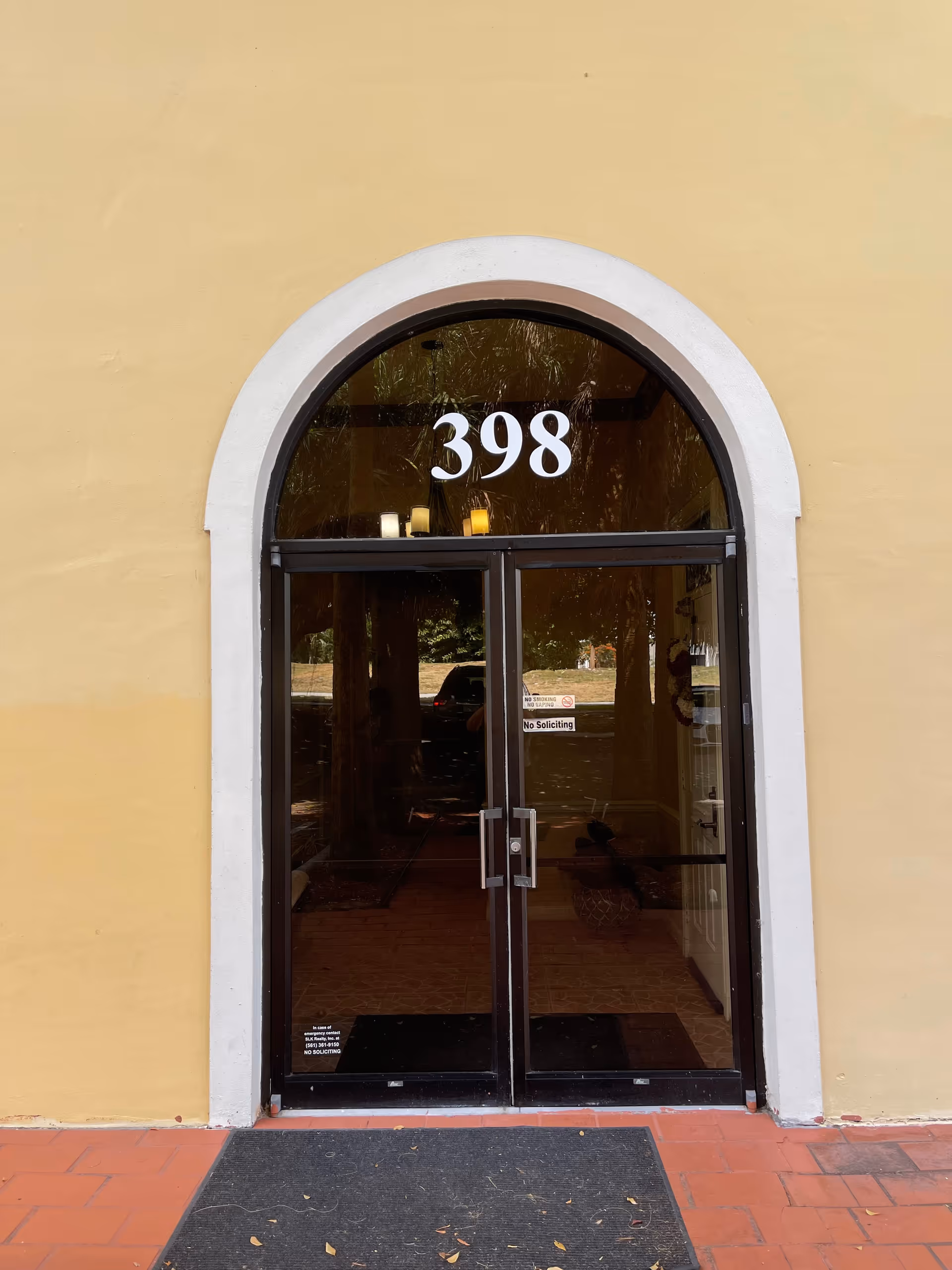 Yellow building facade with an arched glass door and the number 398.