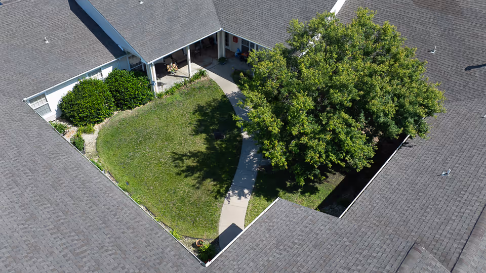 Aerial view of a senior living facility courtyard with lawn and tree.