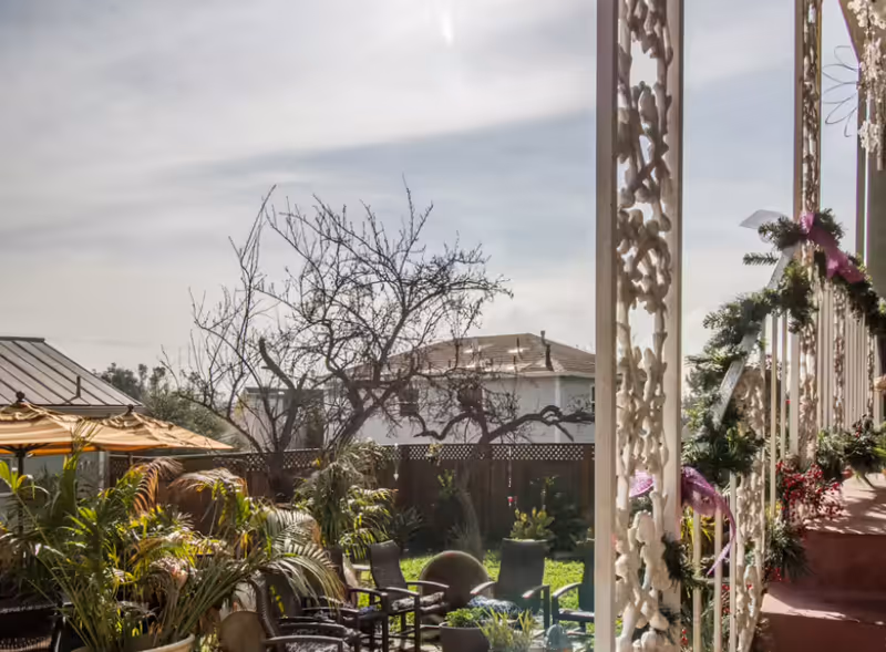 Outdoor patio with seating, plants, and decorative columns along a walkway.