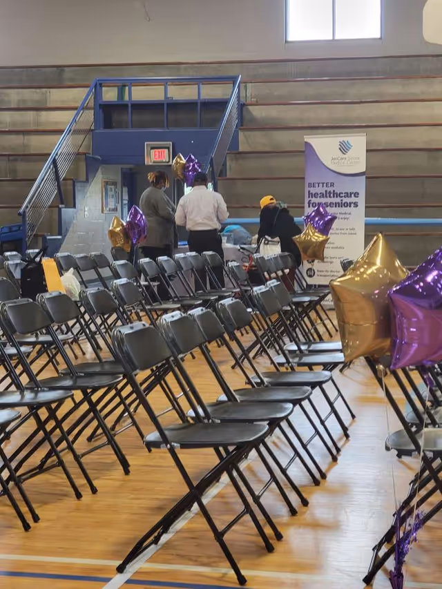 Indoor hall with rows of black folding chairs and balloons for an event