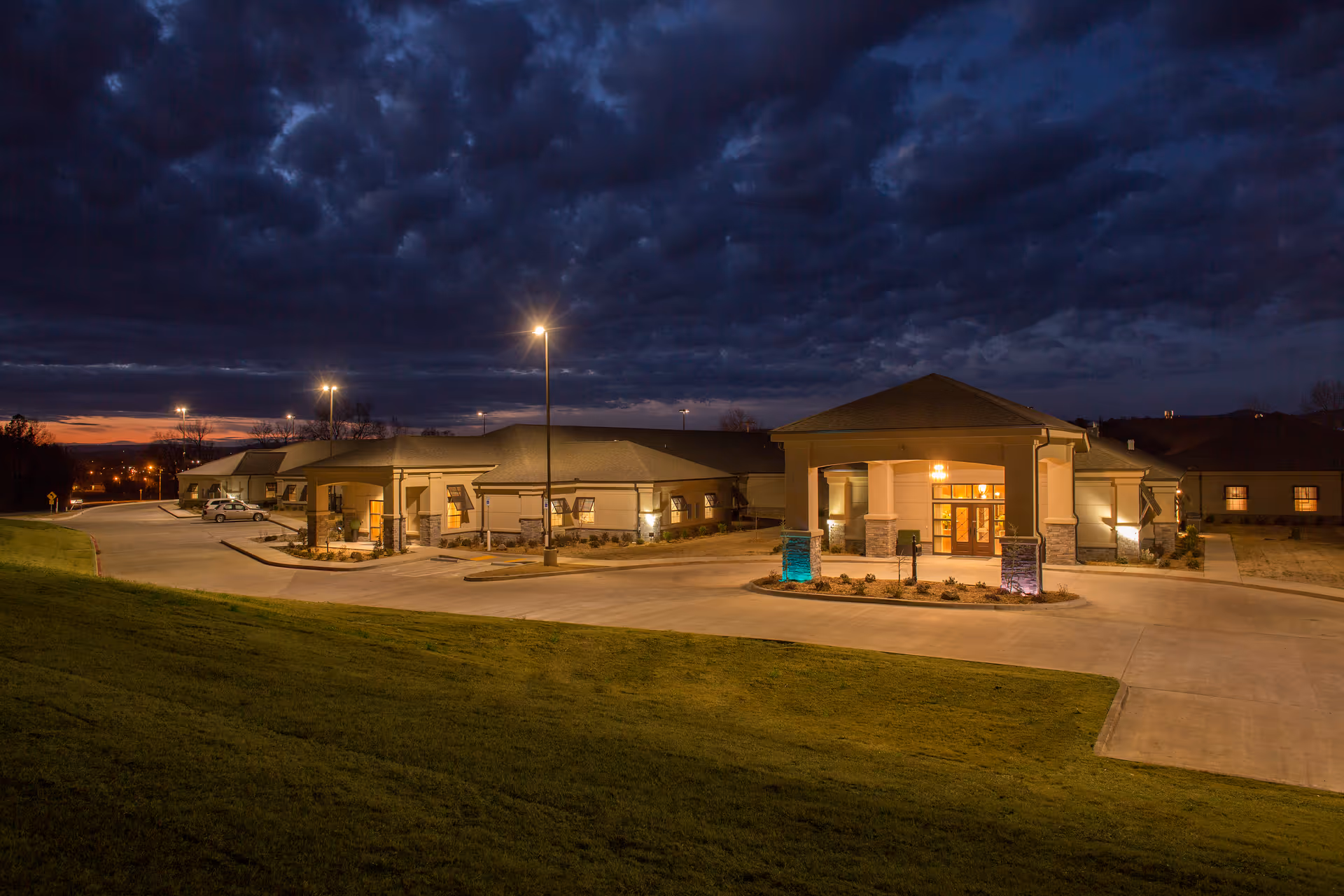 Exterior view of Johnson County Health and Rehab facility at dusk, illuminated entrance, curved driveway.