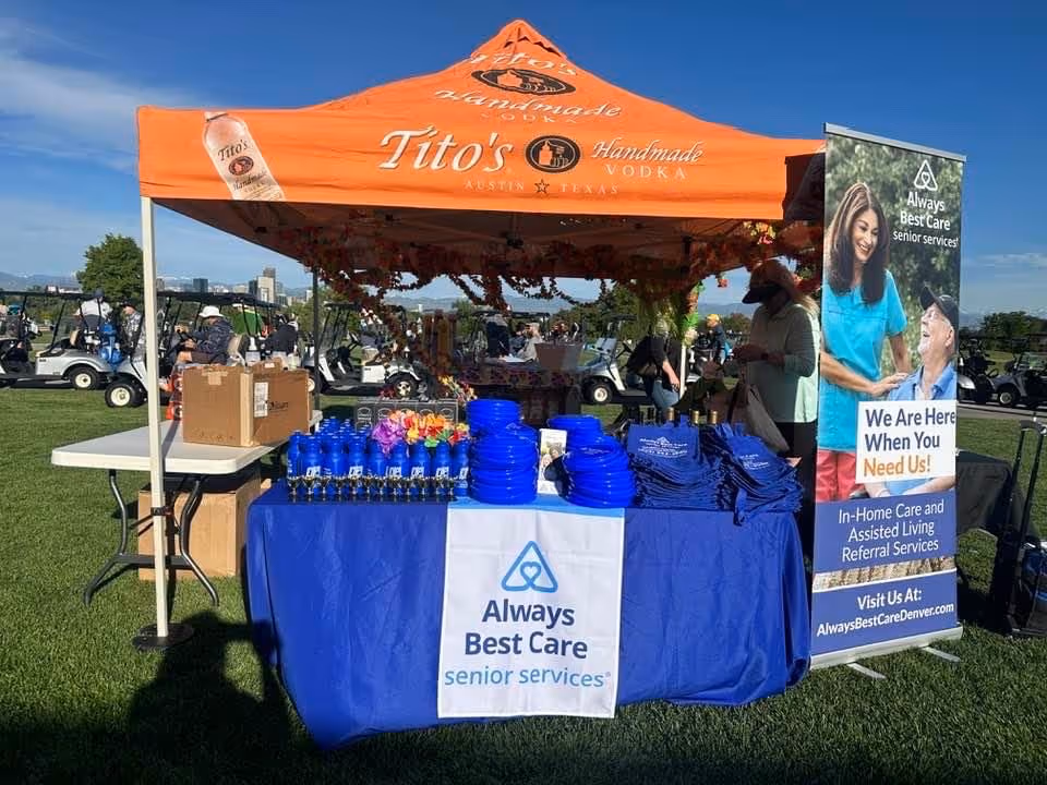 Outdoor event booth for Always Best Care with orange tent and blue table.