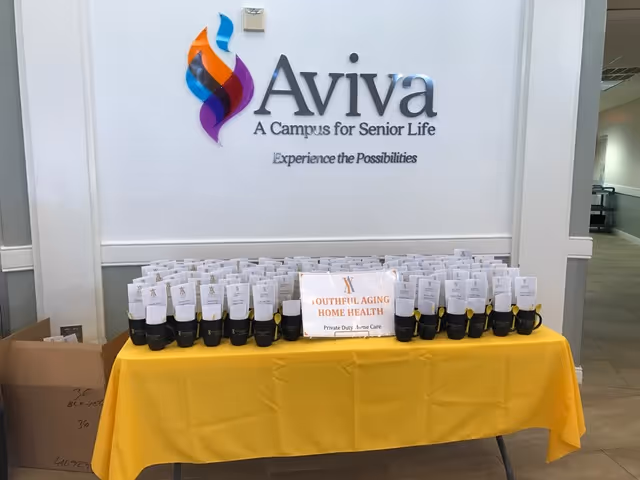 Table with yellow cloth displays many bottles in front of an Aviva interior wall sign.