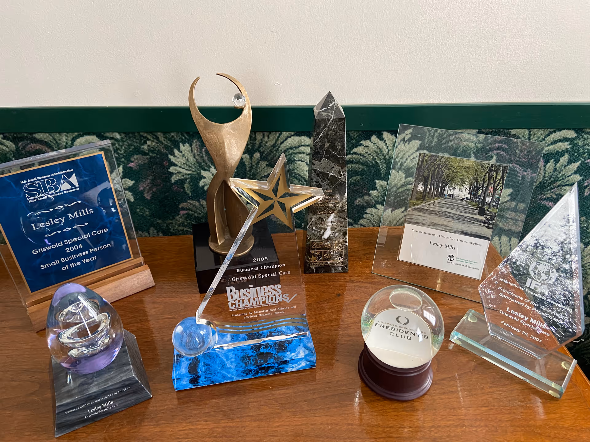 Glass awards and trophies displayed on a wooden table inside Griswold Home Care for New Haven.