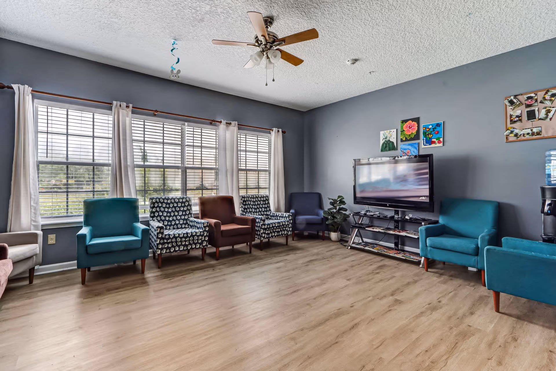 Lounge area in Amelia Springs Assisted Living with multiple chairs, a TV, and large windows.