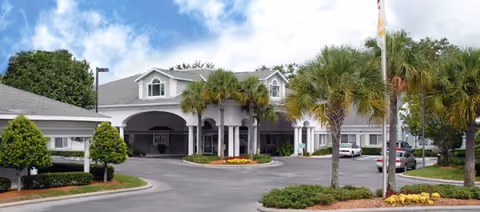 Front view of Life Care Center of Orange Park with palm trees and parked cars.