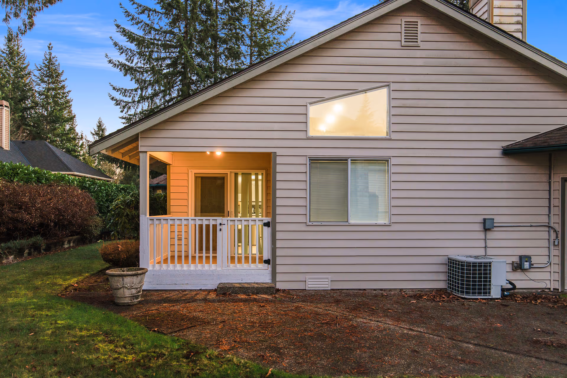 Beige house exterior with a small front porch, white railing, window, and visible outdoor unit.