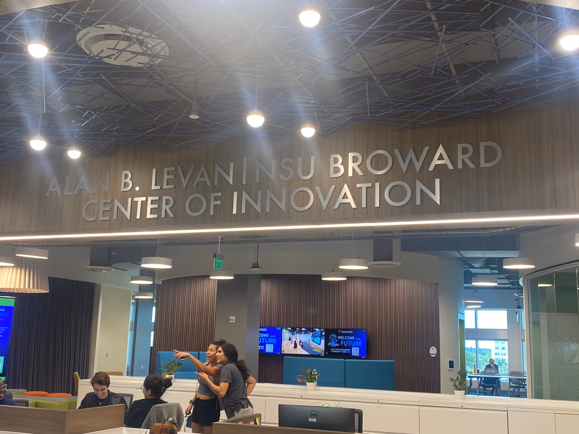 Interior lobby of a modern innovation center with a large sign and people seated.