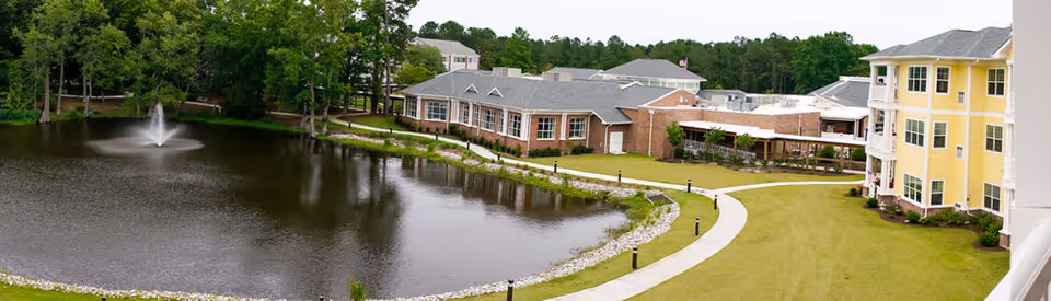 Exterior view of Porters Neck Village with a pond, fountain, and campus buildings.