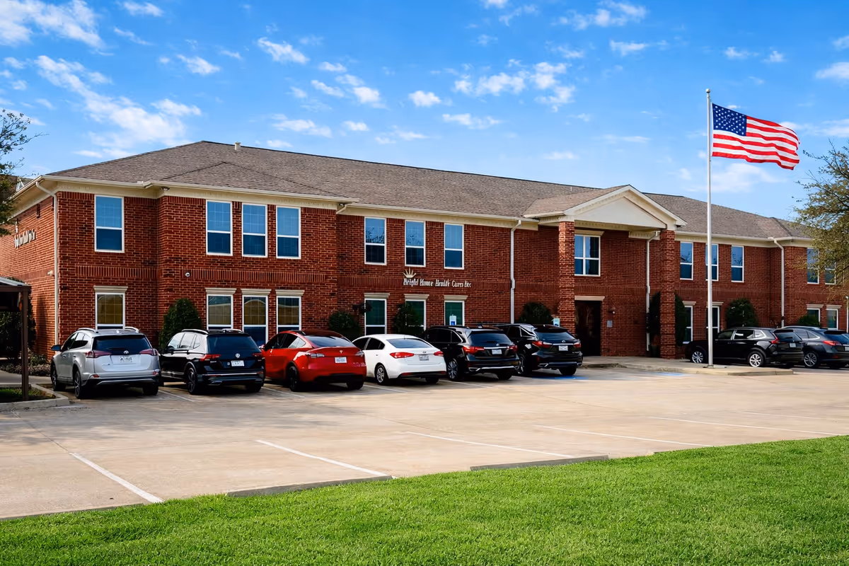 Two-story red brick Bright Home Health Care building with cars in front and American flag