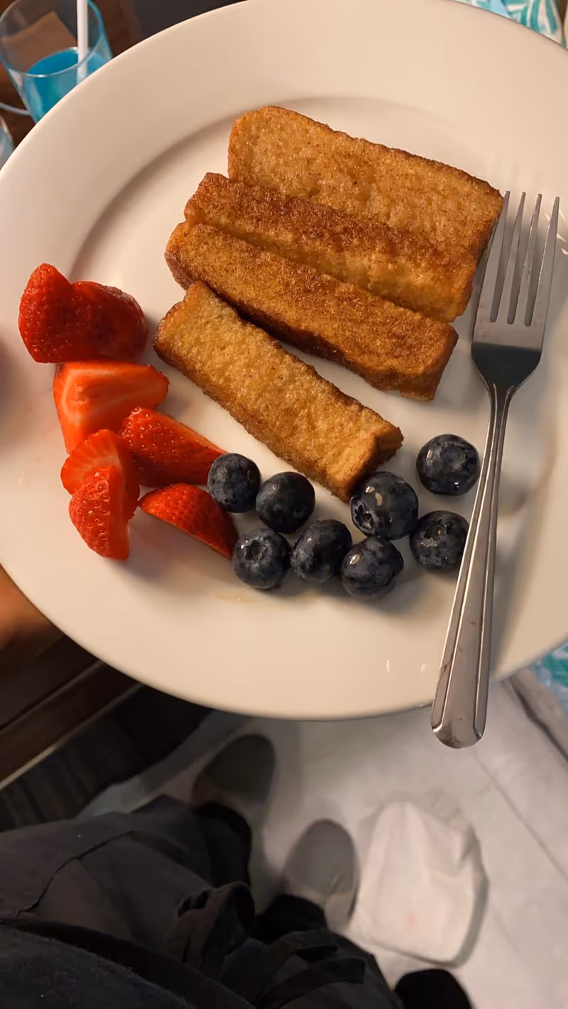 Plate with toast sticks, strawberries, and blueberries on a dining table.