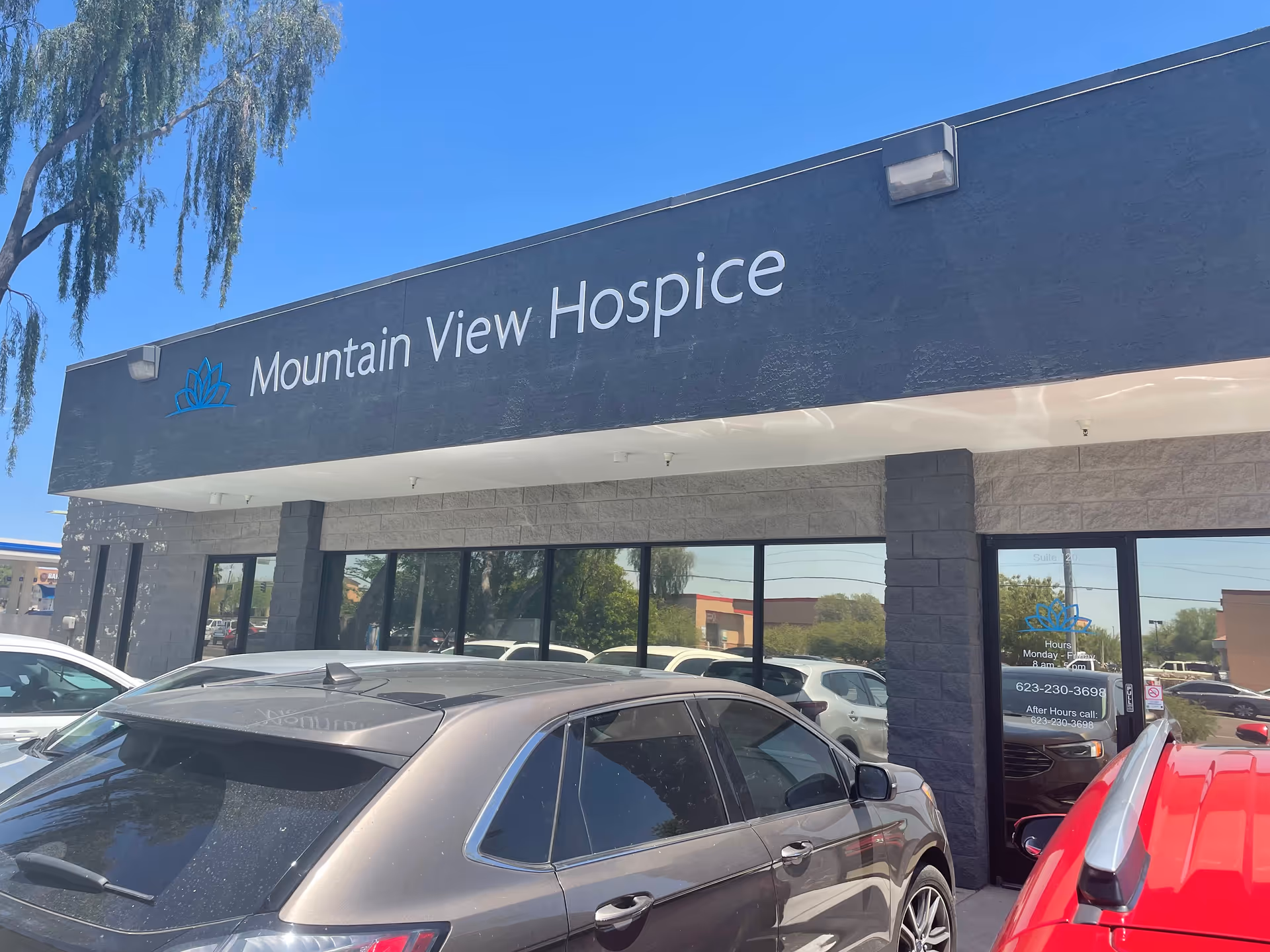 Exterior of Mountain View Hospice building with signage, windows, and parked cars.