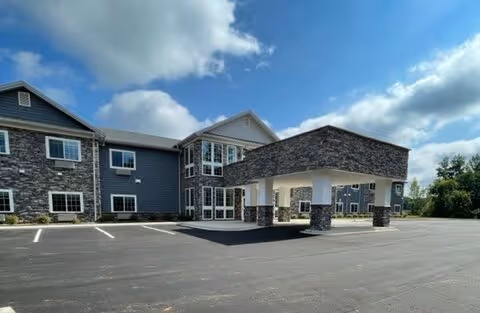 Exterior view of a two-story senior living facility with a covered entrance and parking.