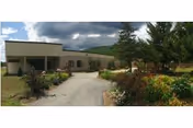 Front view of Elderwood at North Creek exterior with a walkway and landscaped garden.
