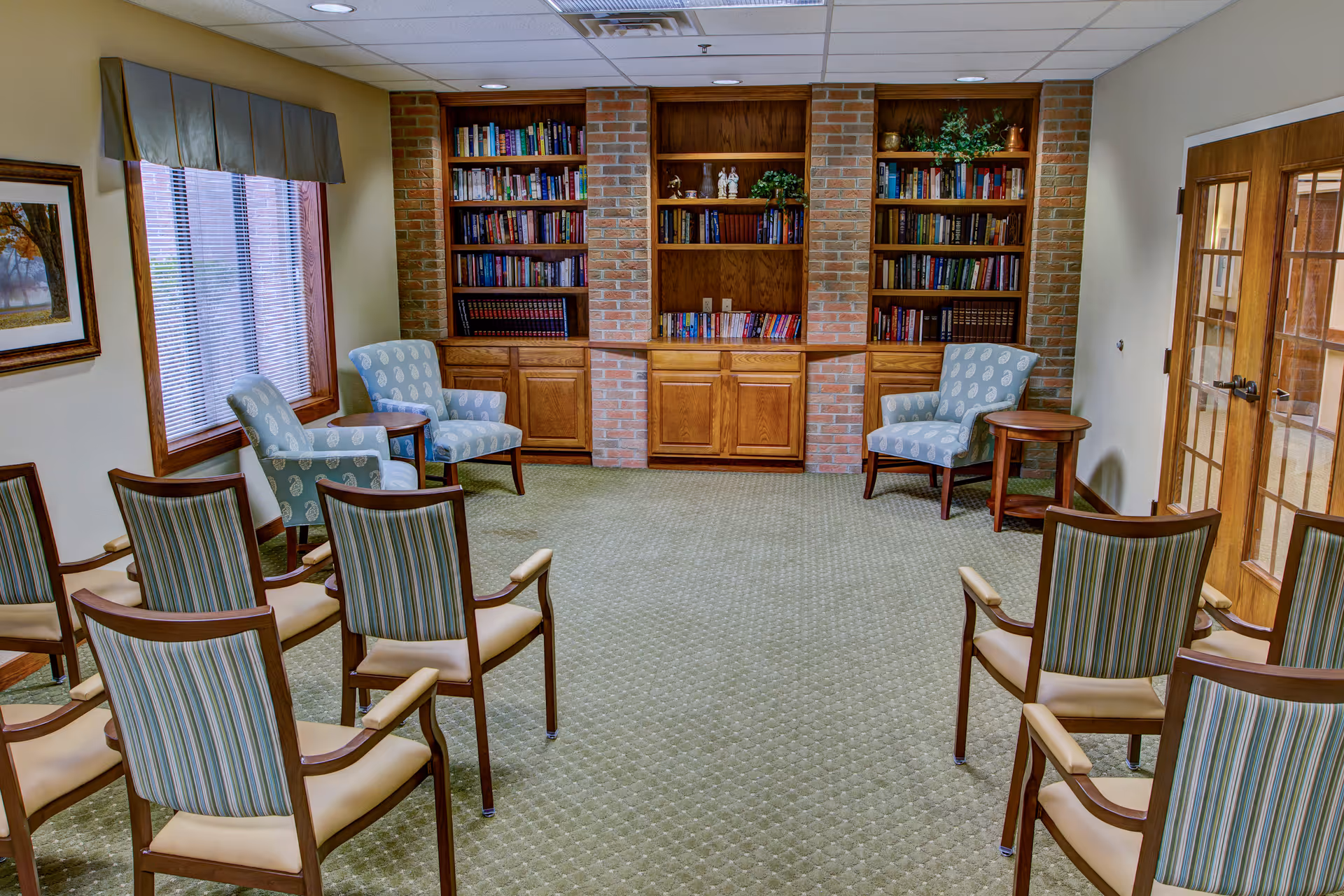 Cozy library reading room with brick bookcases and blue upholstered chairs.