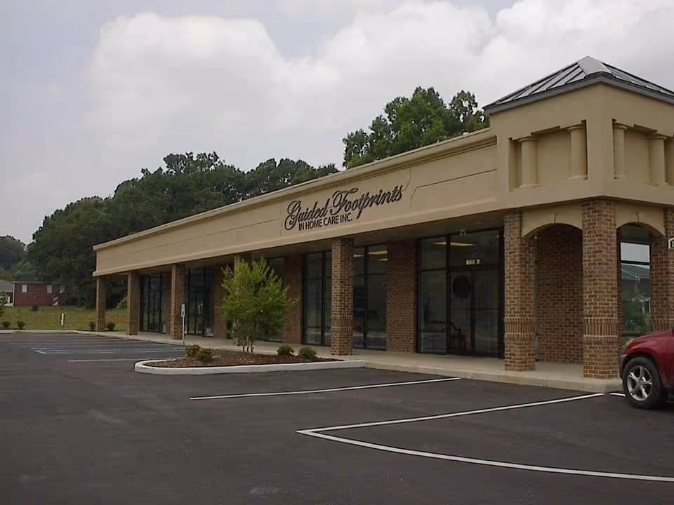 Exterior view of Guided Footprints In Home Care storefront with parking lot and trees.