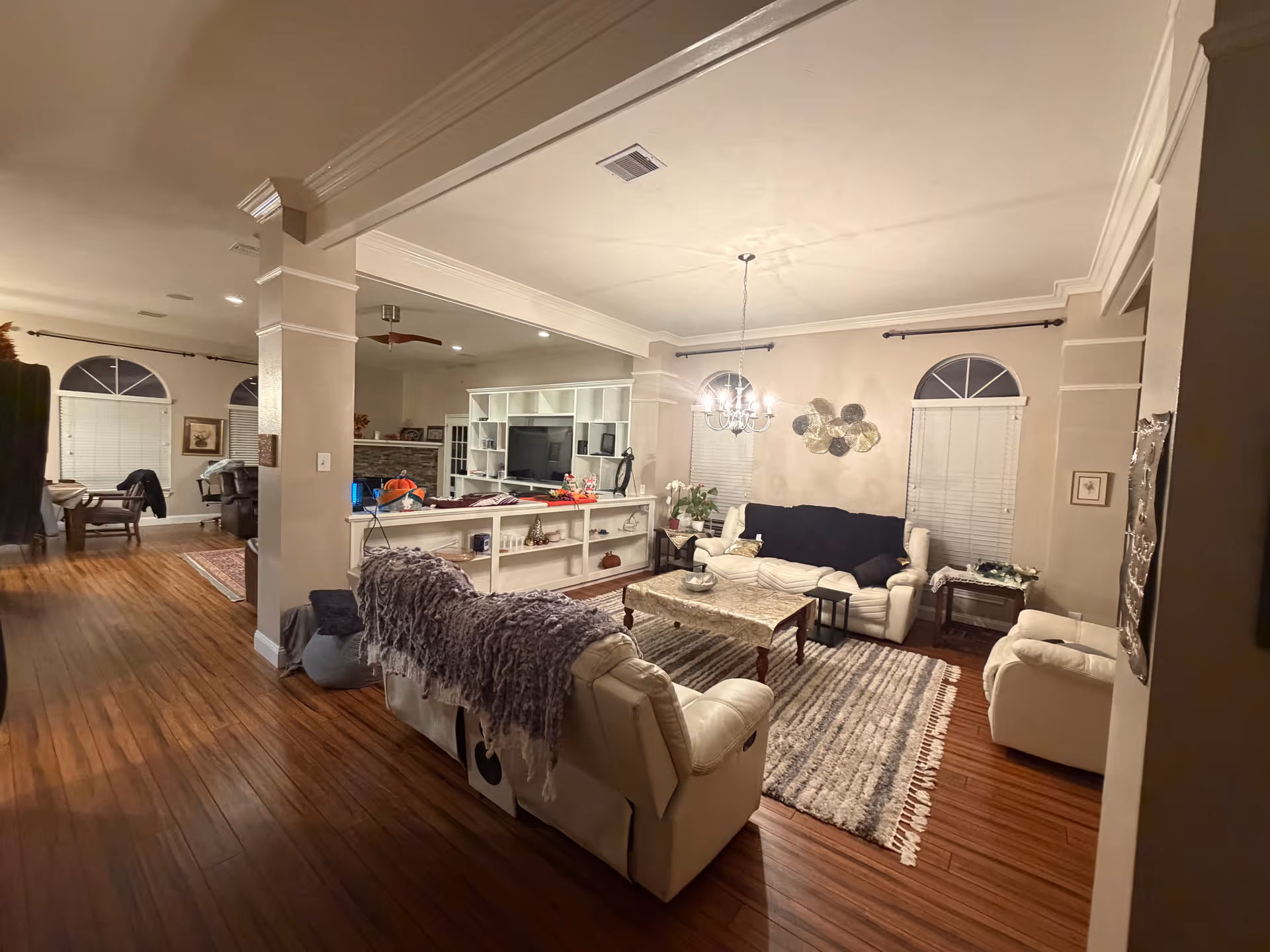 Spacious living room with white sofas, a coffee table, chandelier, and built-in shelving.