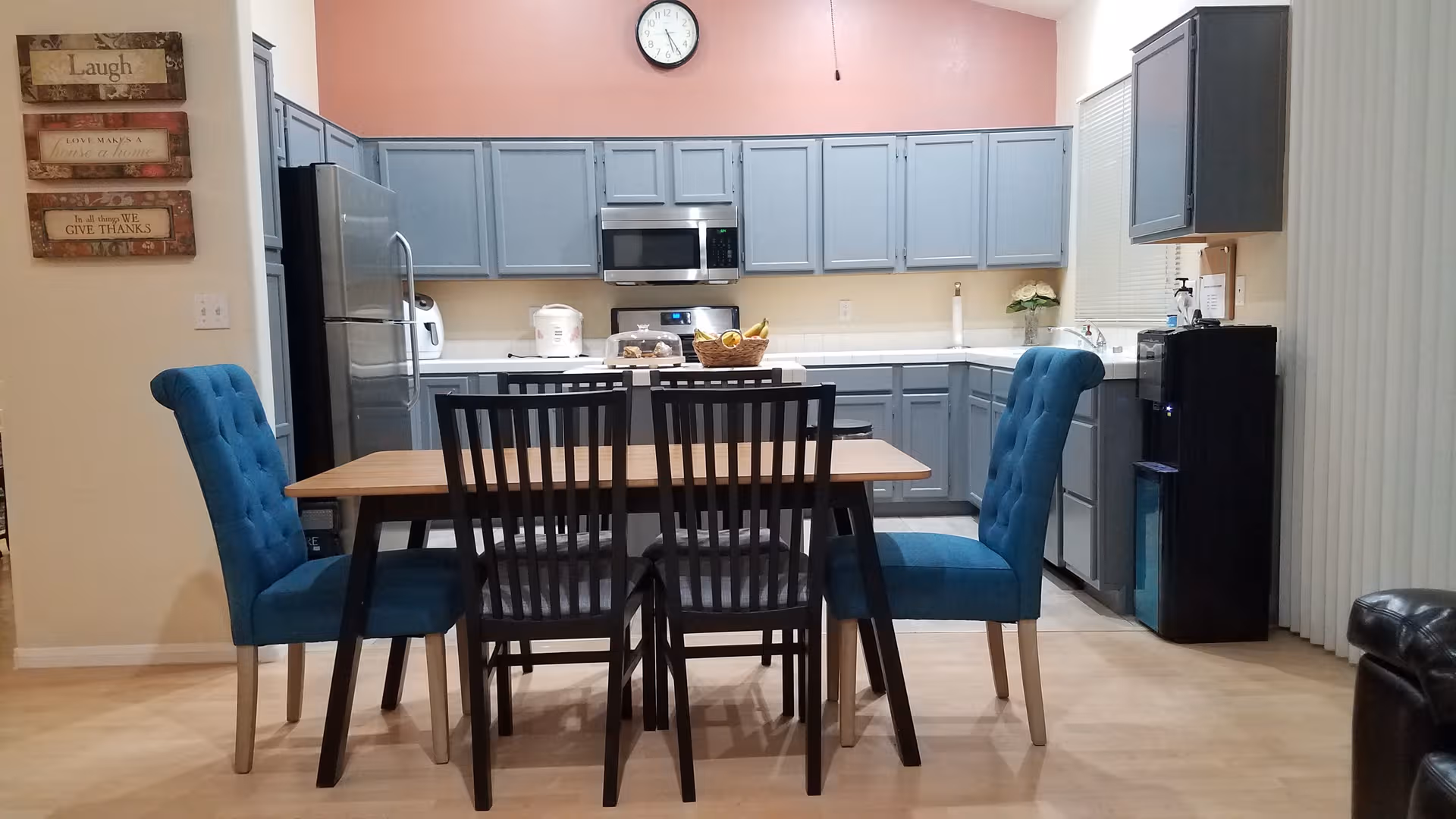 A dining table with blue upholstered chairs in a kitchen-style dining area.