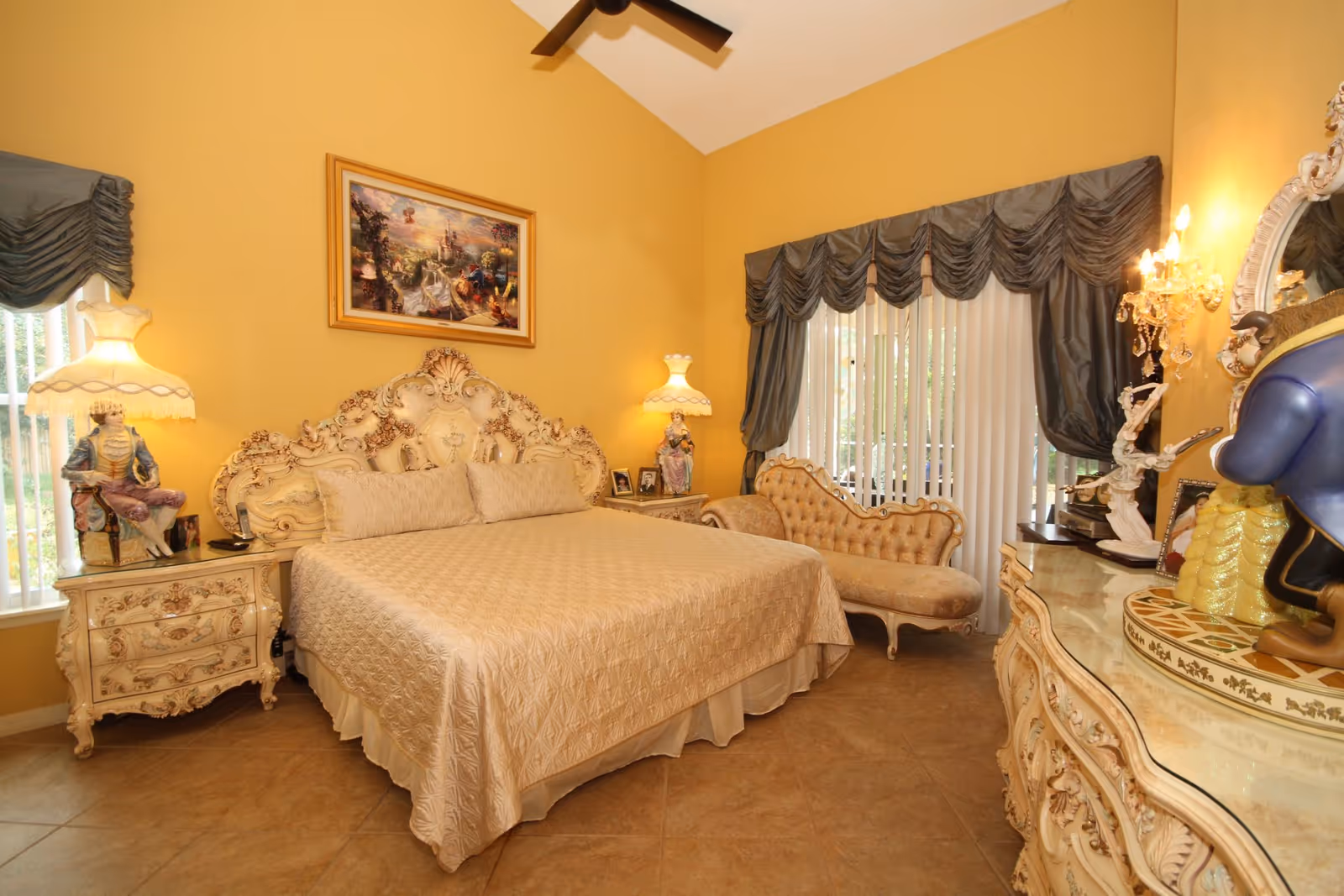 Luxurious ornate bedroom with cream bed, chaise lounge, and vintage furnishings.