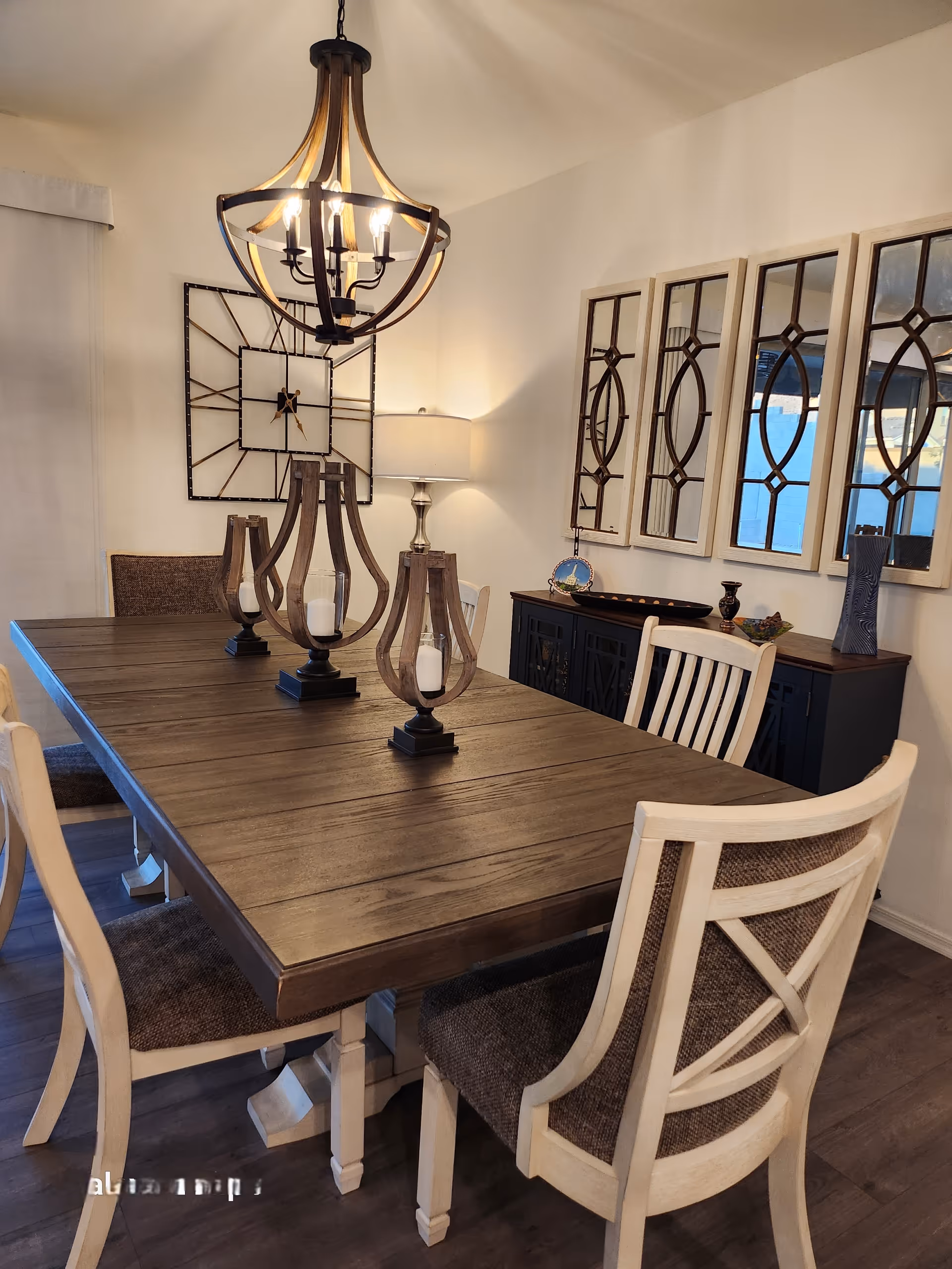 Large wooden dining table with chairs, chandelier, and wall mirrors in a dining room.