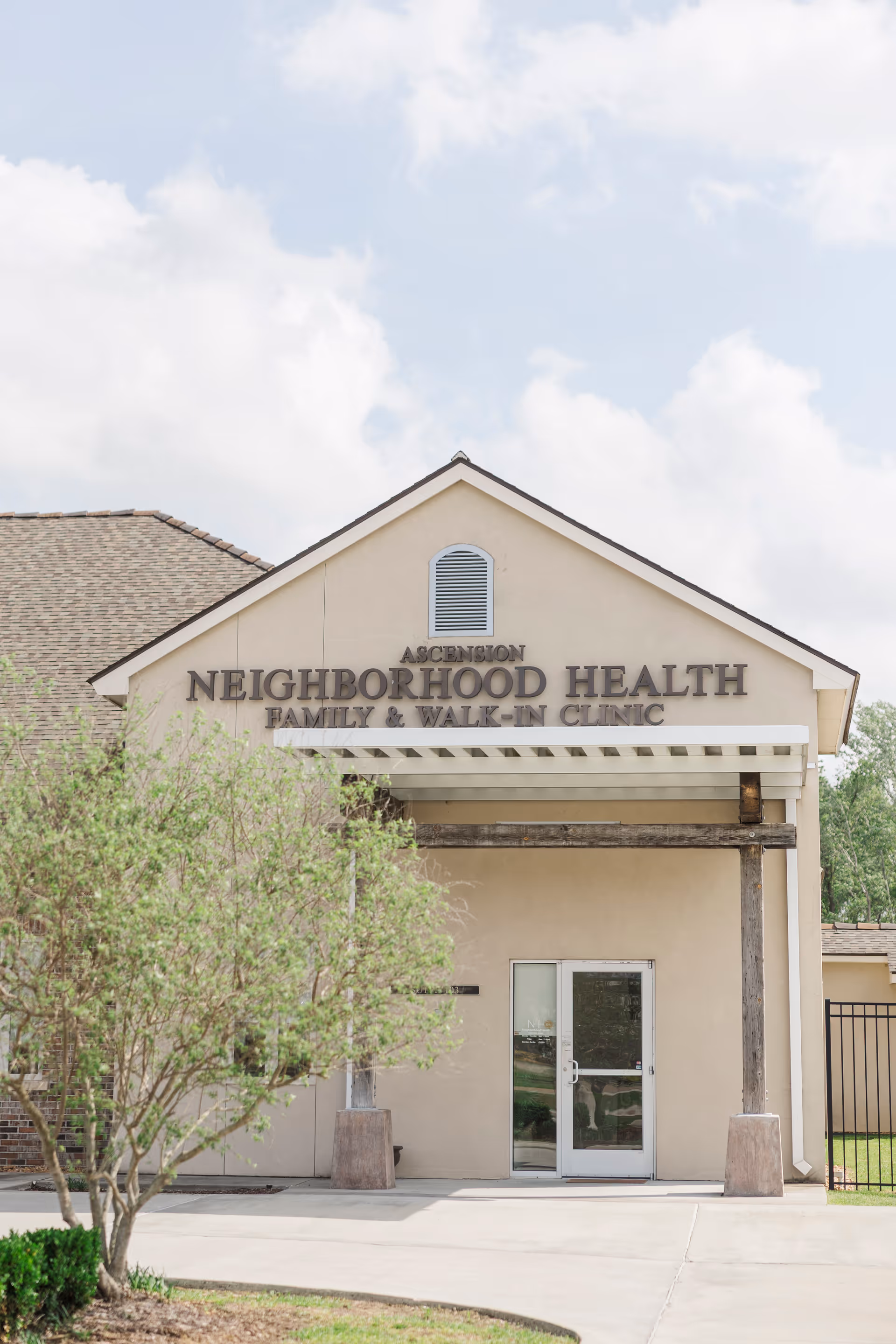 Front exterior of Neighborhood Health clinic with beige walls and a glass entrance door.