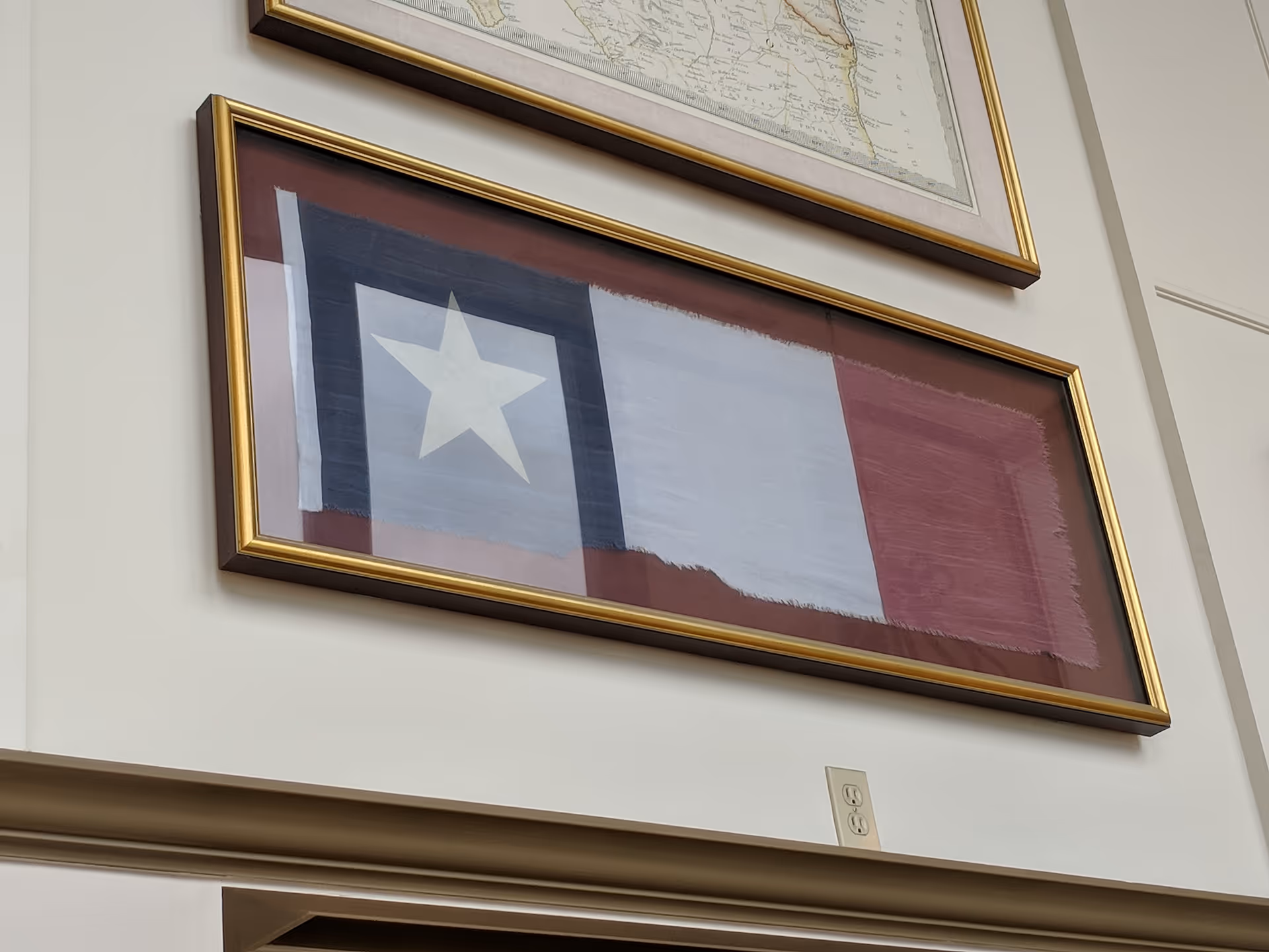 Interior wall with framed Texas flag artwork hanging in a bright room.