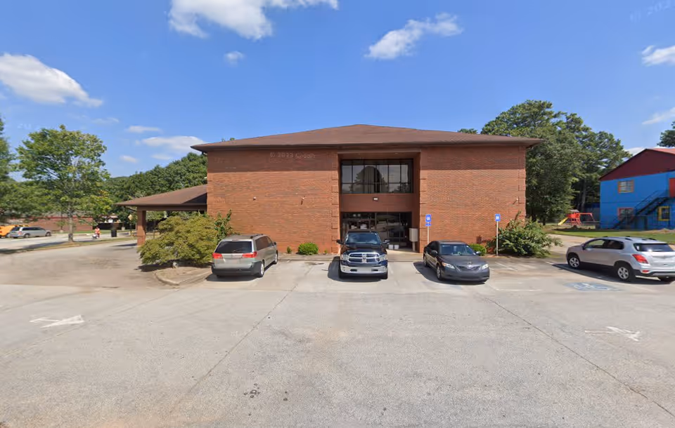 Front view of a brick senior living facility with a parking lot.