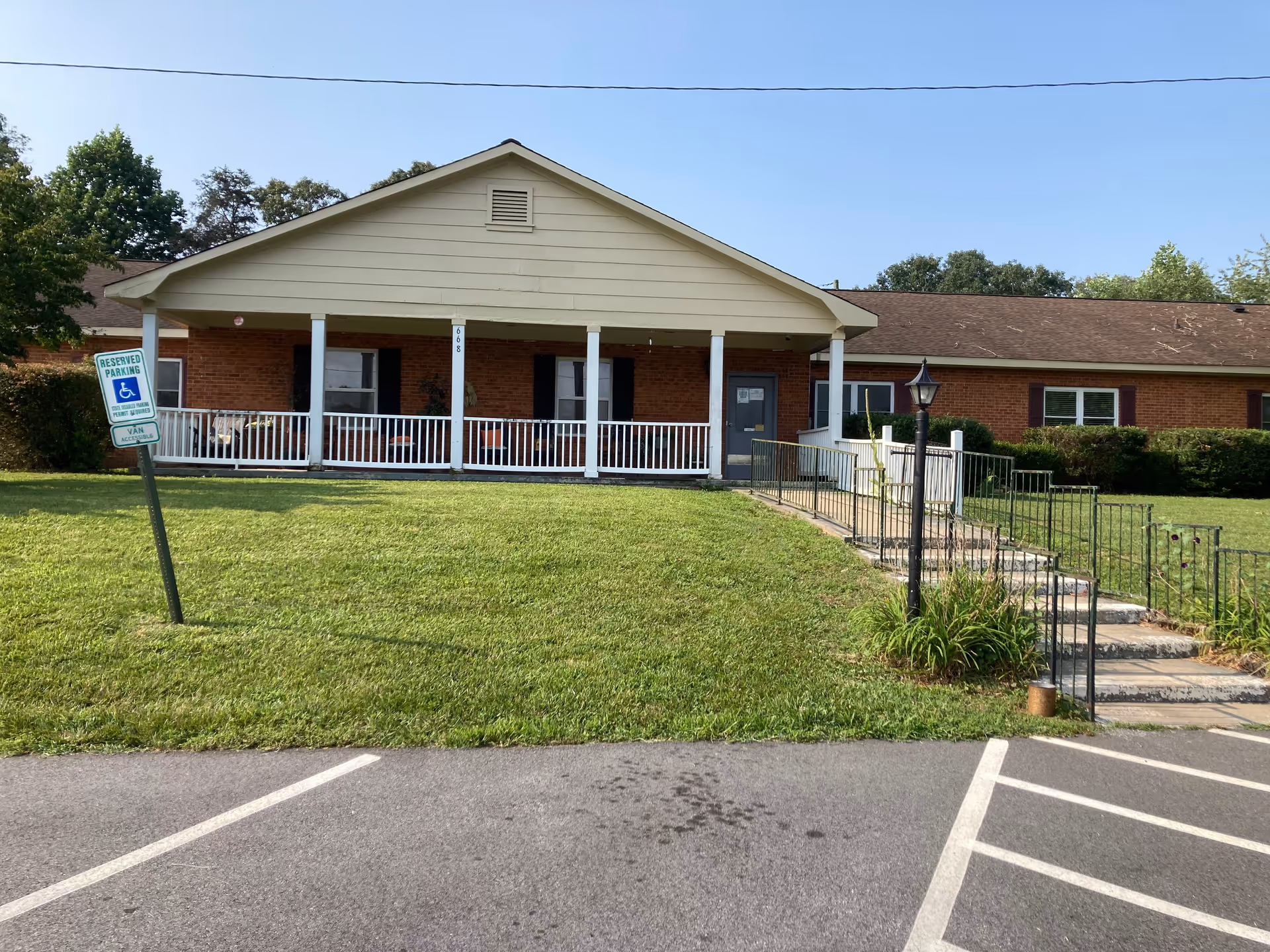 Single-story brick care home with a wide front porch and ramp, surrounded by lawn.