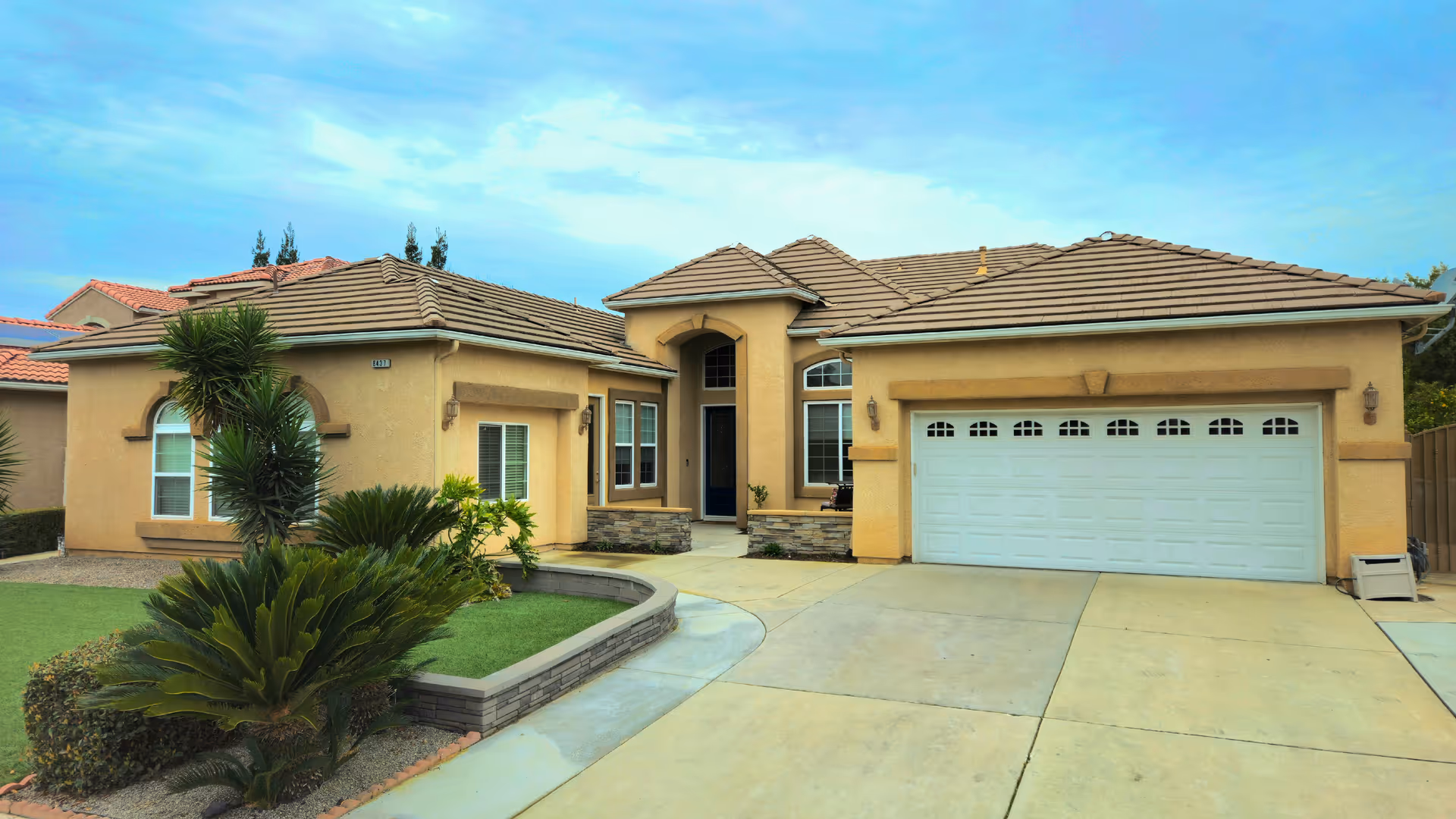 Exterior of a single-story residential care facility with a two-car garage and landscaped front yard.