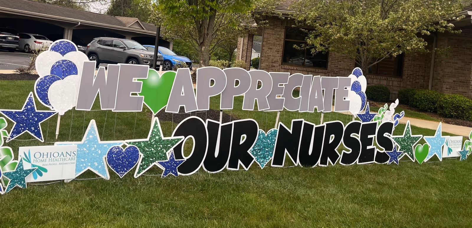 Large outdoor lawn display reading We Appreciate Our Nurses in front of a brick building.