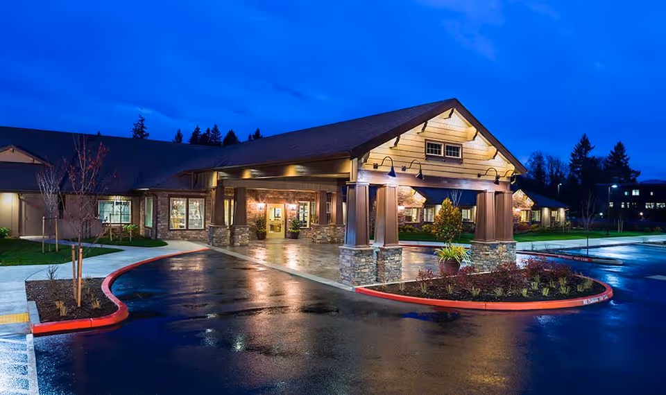 Front entrance of Springs Ranch Memory Care Community at dusk with a covered porte-cochère and wet driveway.
