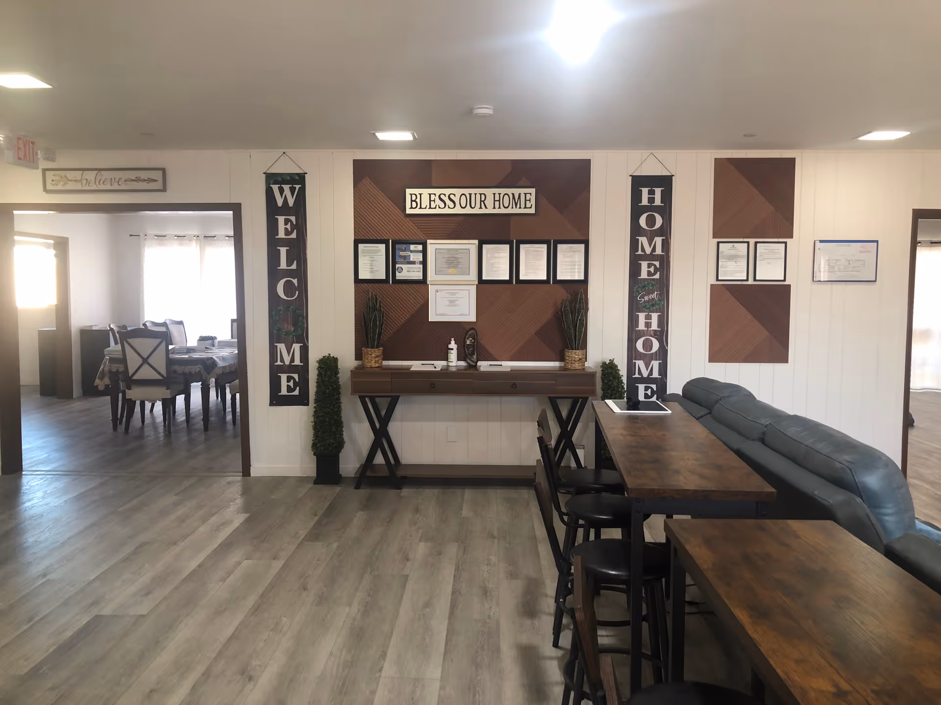 Interior common area with a sofa, long tables, signs, and framed certificates.