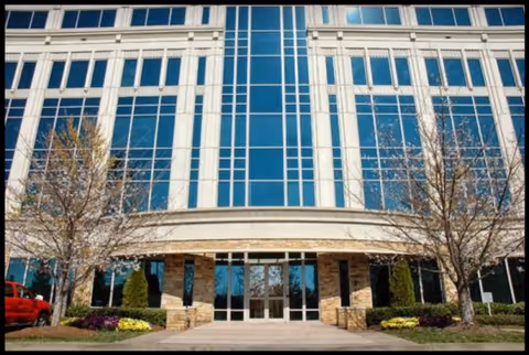 Front exterior of Open Arms & Loving Hands senior living facility with glass windows and entrance.
