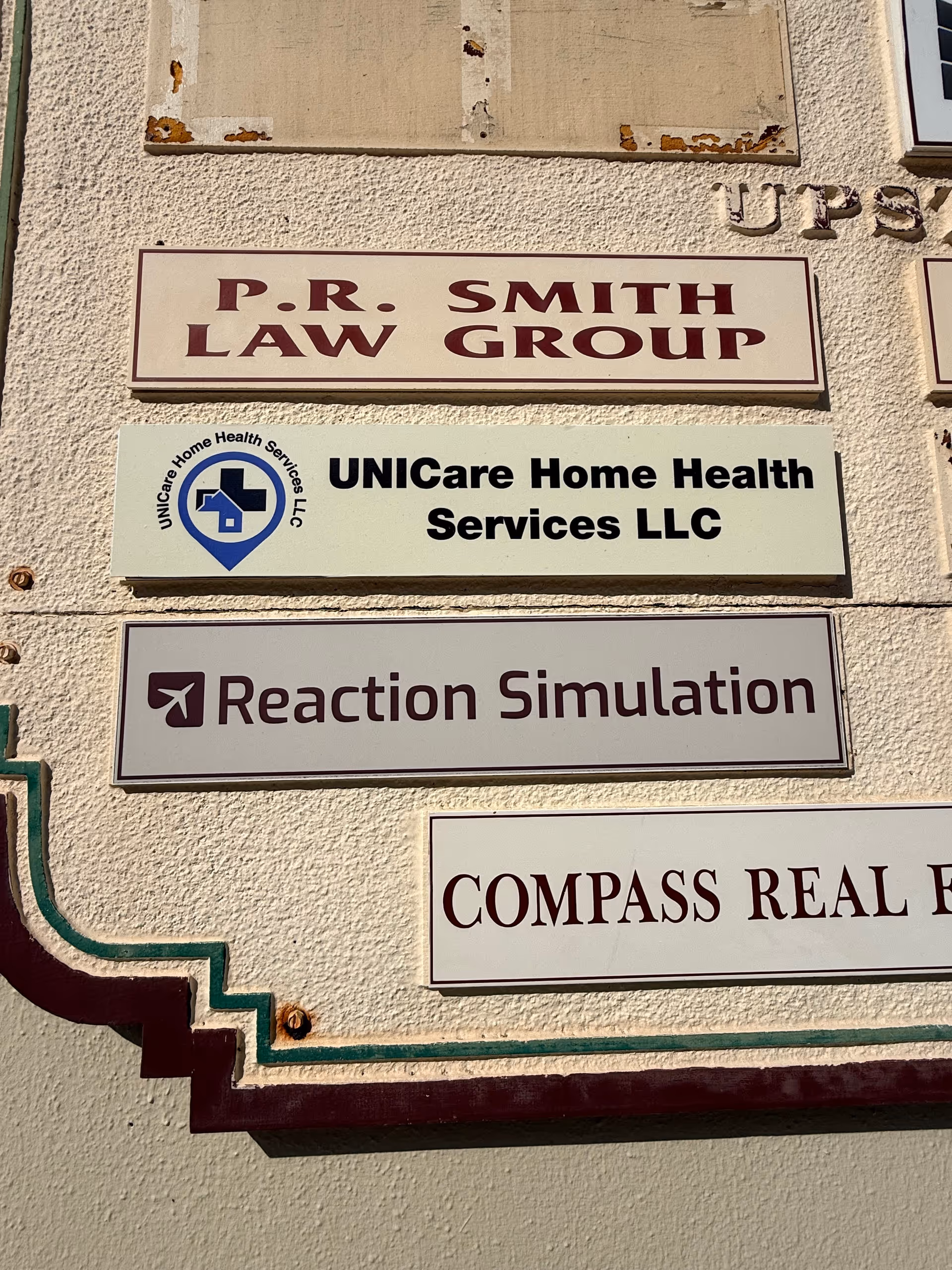 Exterior wall signage showing UNICare Home Health Services LLC beside other business signs.