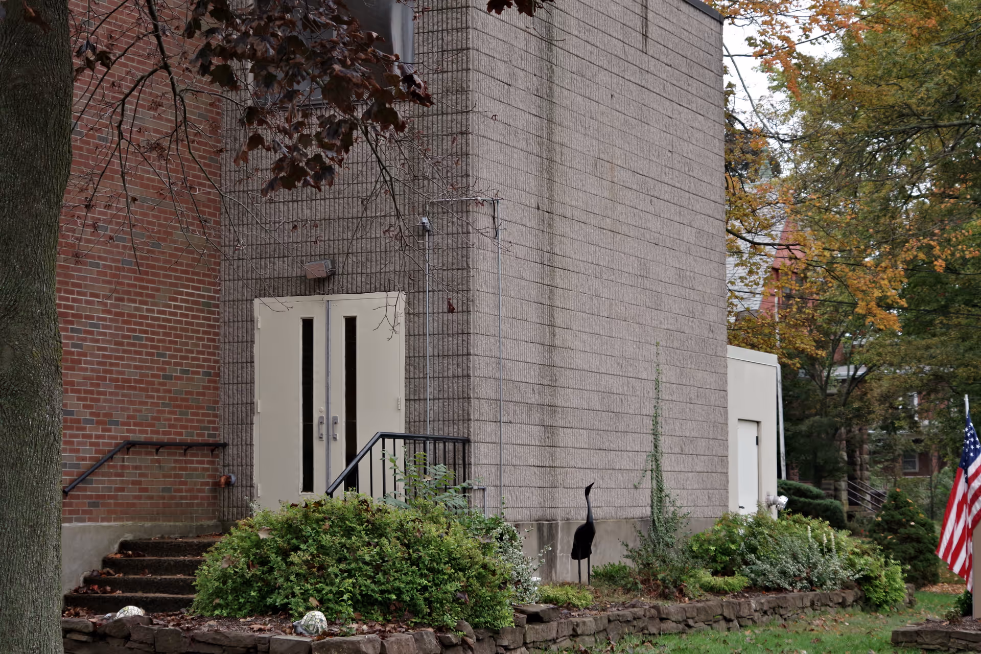 Exterior view of a brick building with double doors, steps, and landscaping.