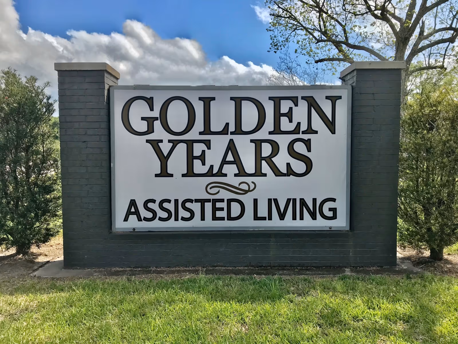 A large outdoor sign reading Golden Years Assisted Living between brick columns.