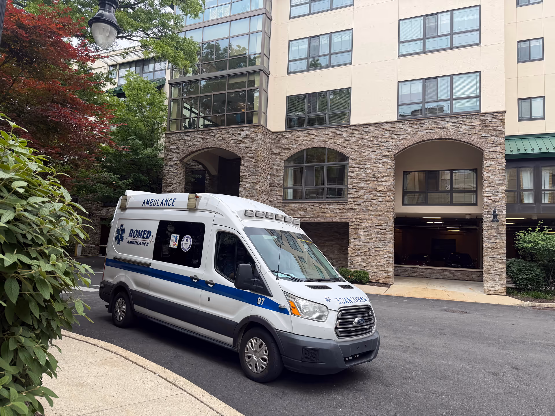 Ambulance parked in driveway at front entrance of stone building.