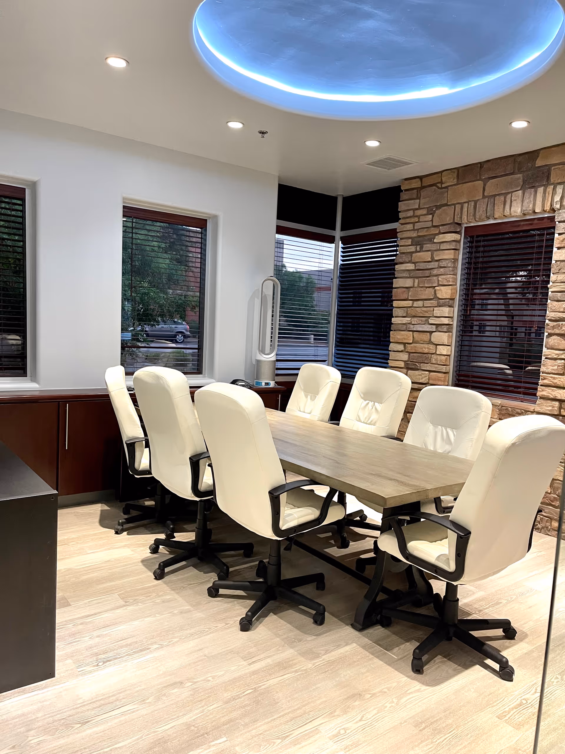 A meeting room with a long table and white swivel chairs inside a senior living facility.