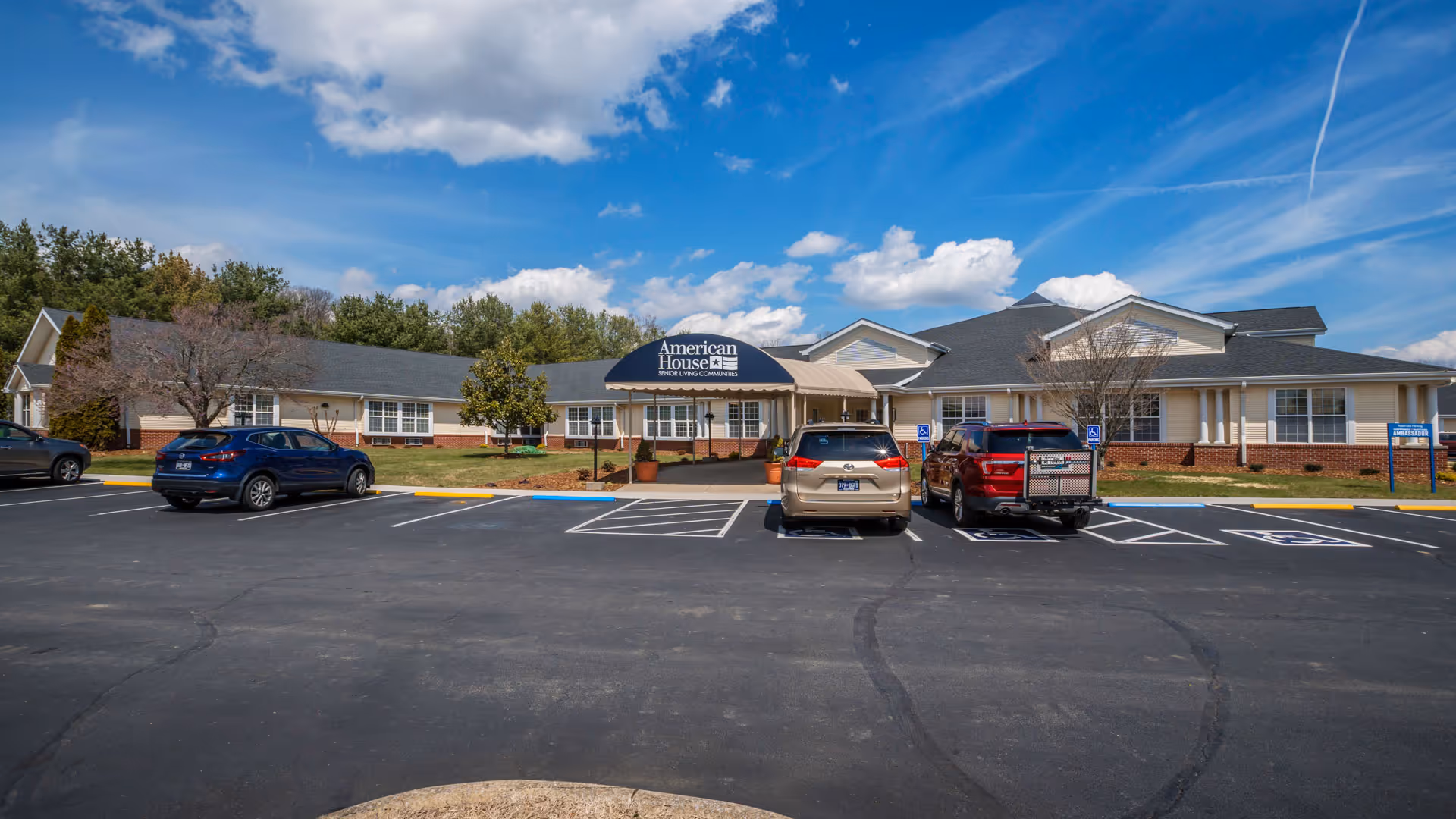 Front exterior of American House Johnson City with parked cars and a central entrance.